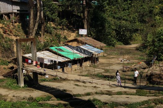 Footbridge over a rustic landscape with huts and greenery, conveying rural life.