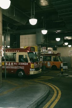 City buses in a dimly lit Hong Kong terminal capturing urban transit.