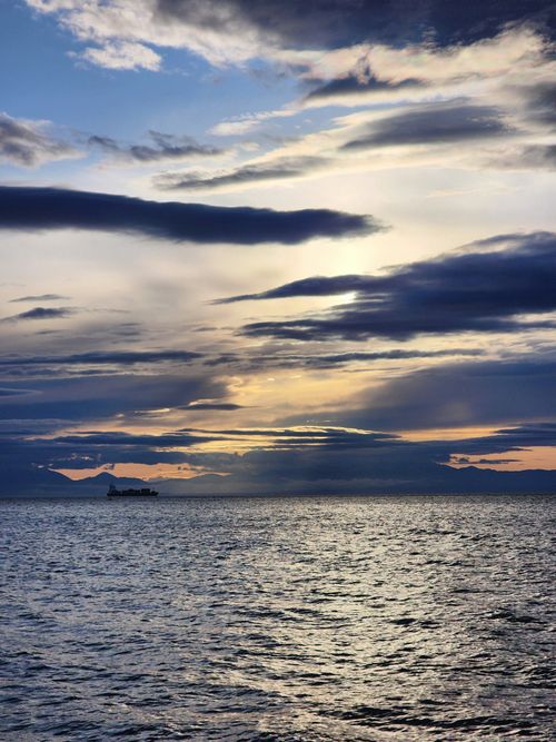Free Beautiful sunset seascape with distant silhouette of a ship under dramatic clouds in Thessaloniki, Greece. Stock Photo