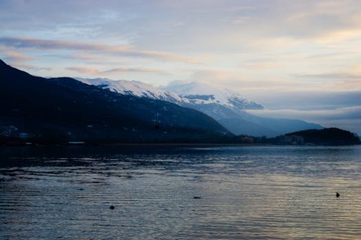 Breathtaking view of Ohrid's tranquil lake with snow-capped mountains at dawn.