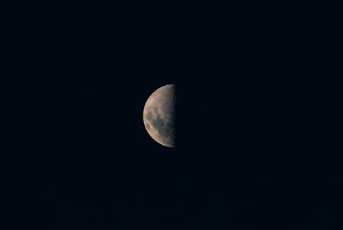 Free Detailed photograph of a half moon against a dark night sky, highlighting lunar features. Stock Photo