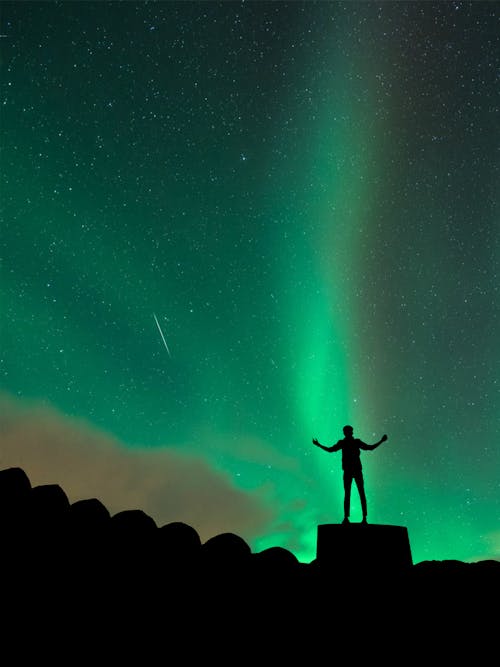 Ücretsiz Yıldızlı Gecenin Altında Kayanın üzerinde Duran Adam Silüeti Stok Fotoğraflar