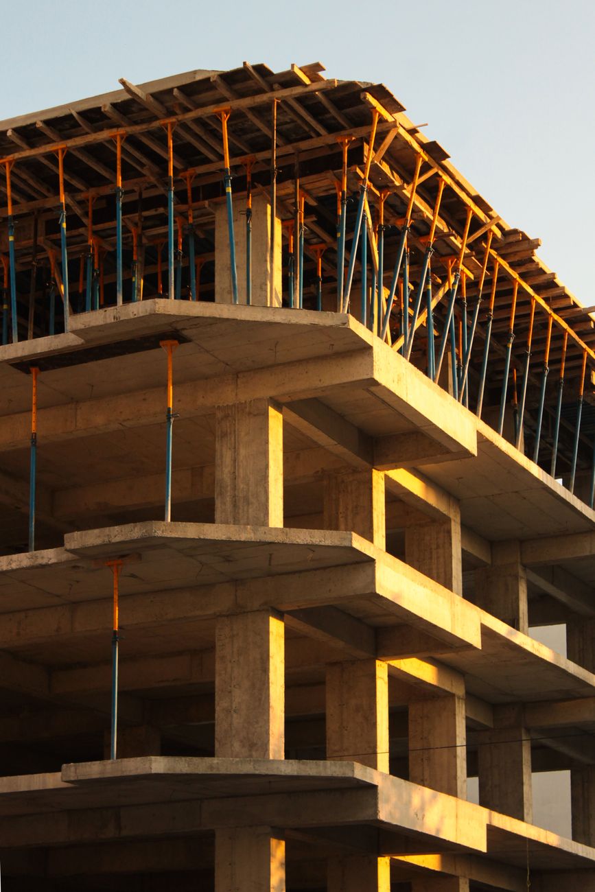 Concrete structure of a multi-story building under construction, illuminated by the warm sunset light.