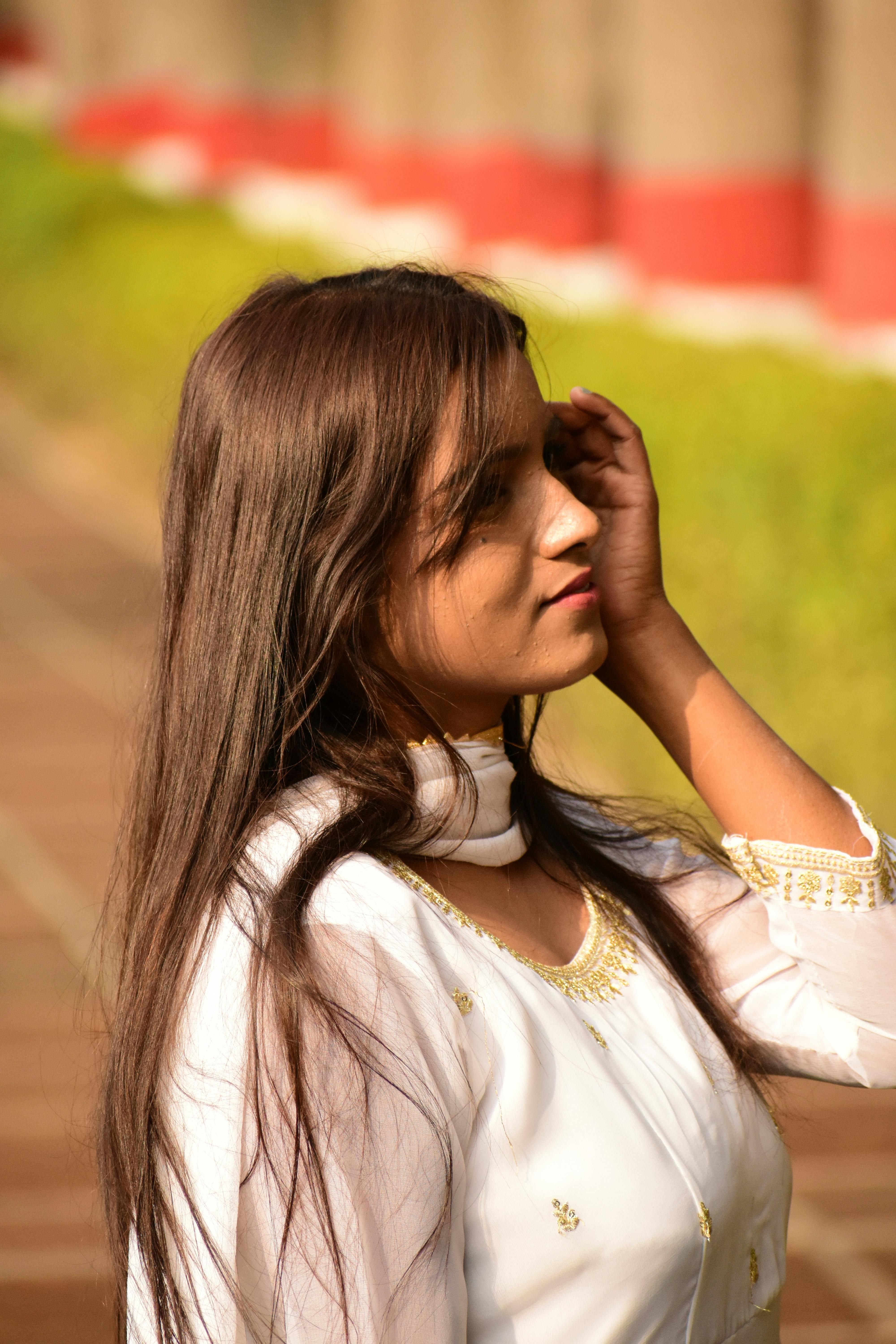 Elegant woman in white traditional attire enjoying the sunlight outdoors.