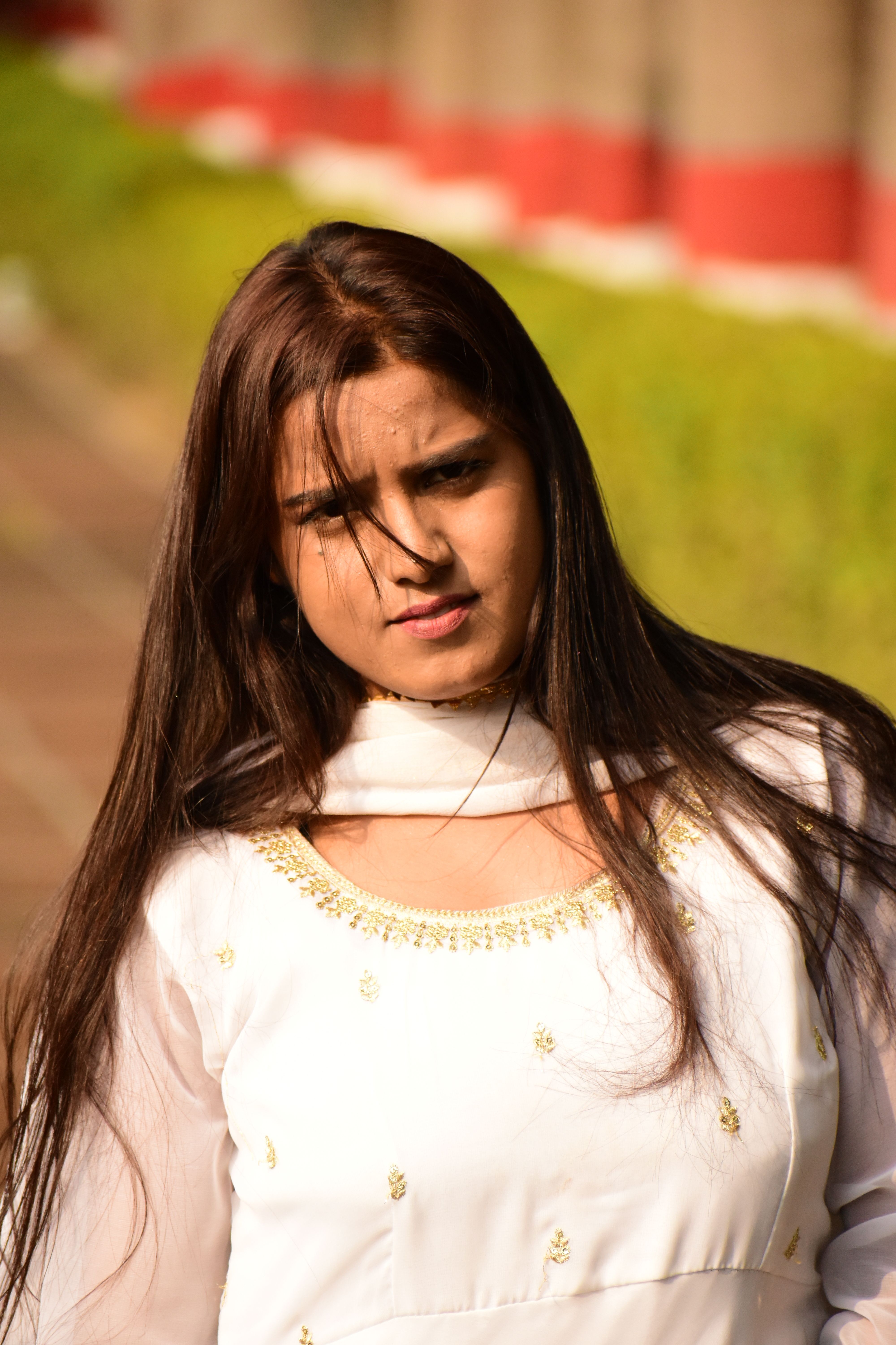 Portrait of a woman in white traditional attire enjoying a sunny day outdoors.
