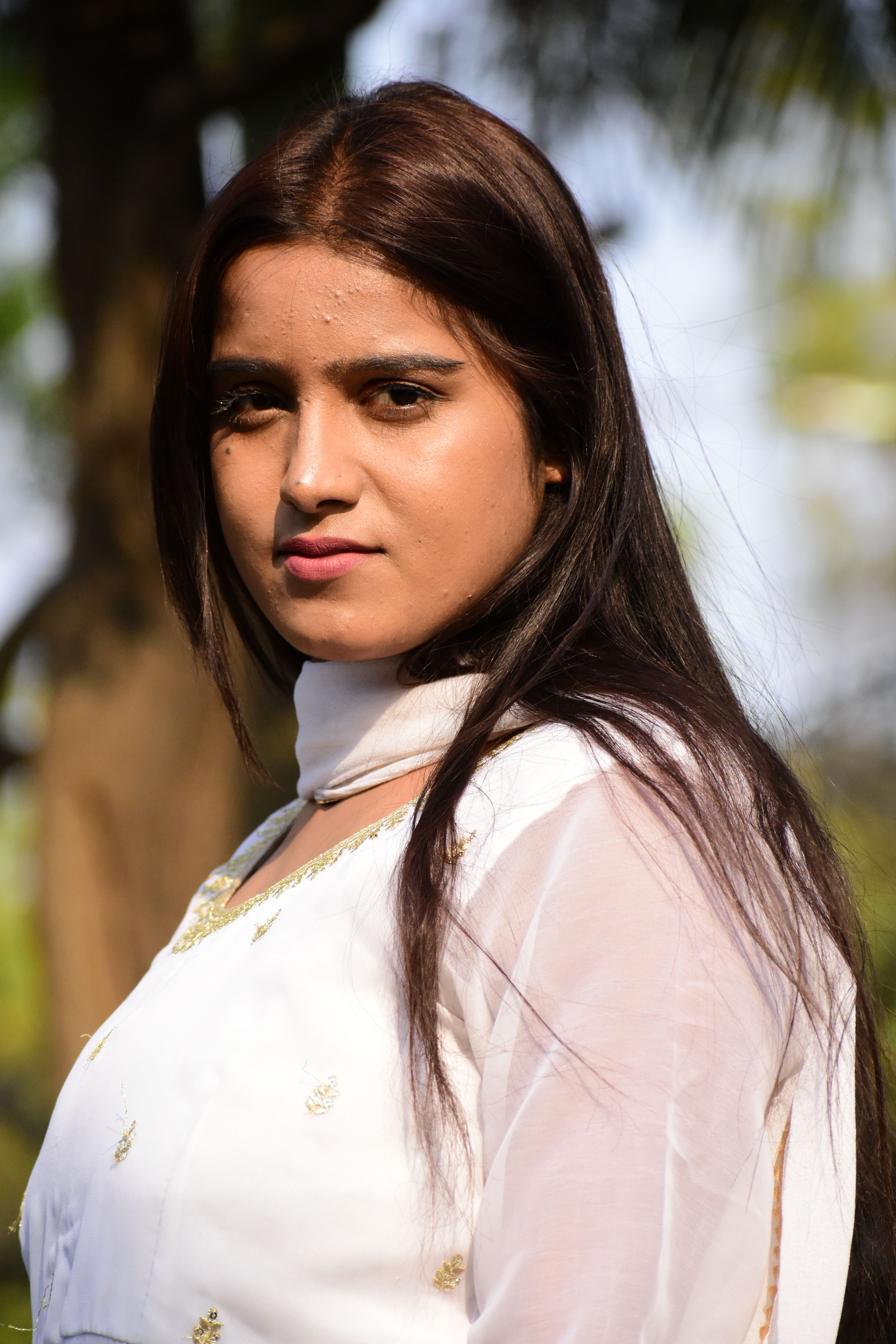 A woman in traditional attire poses confidently outdoors, showcasing elegance and cultural fashion.