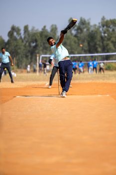 Dynamic shot of a cricketer delivering a ball during a match on a sunny day.