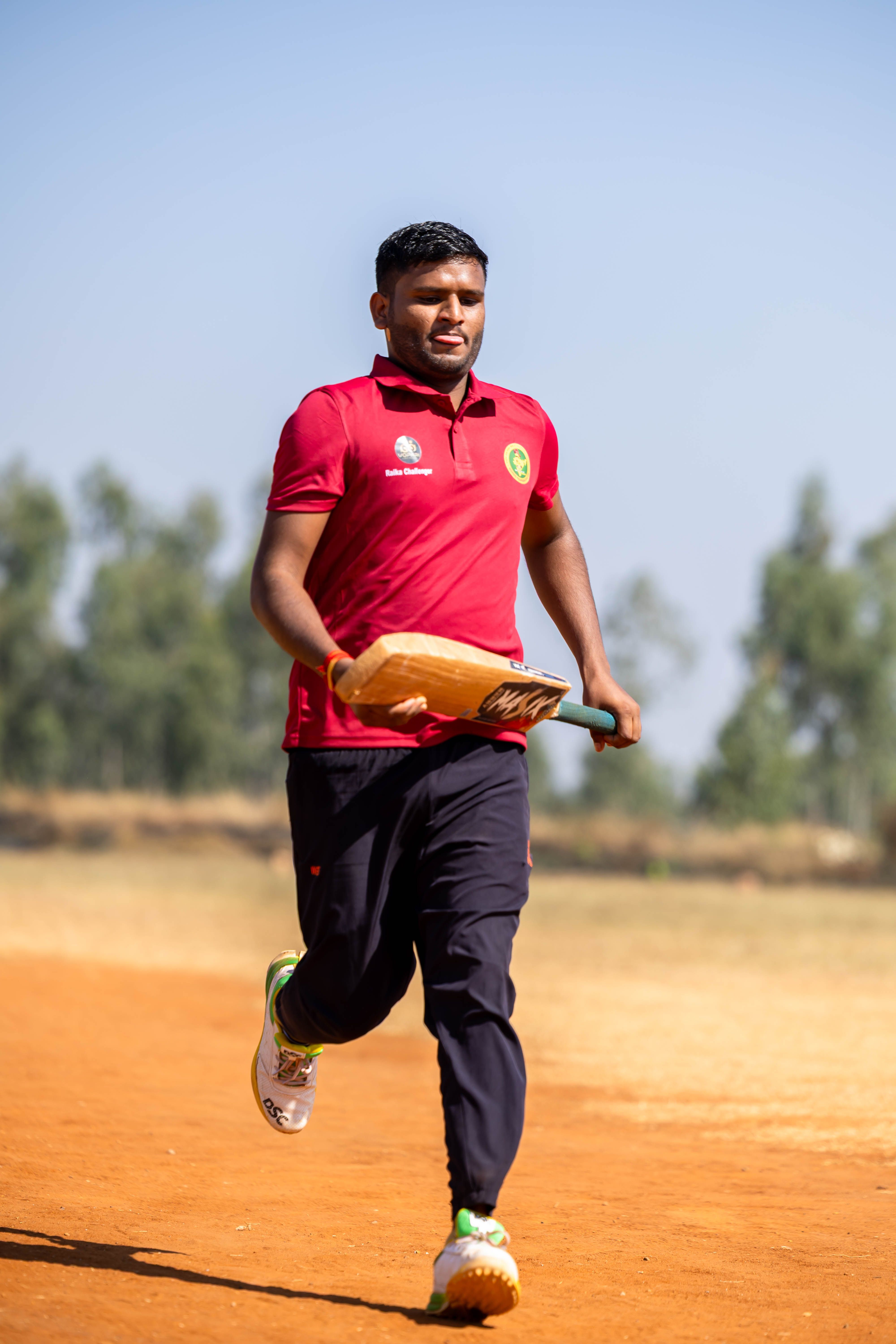 Cricketer running on a field with bat on a sunny day.