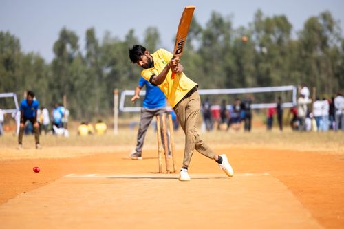 Free A cricketer in yellow shirt hitting a shot during an outdoor match on a sunny day. Stock Photo