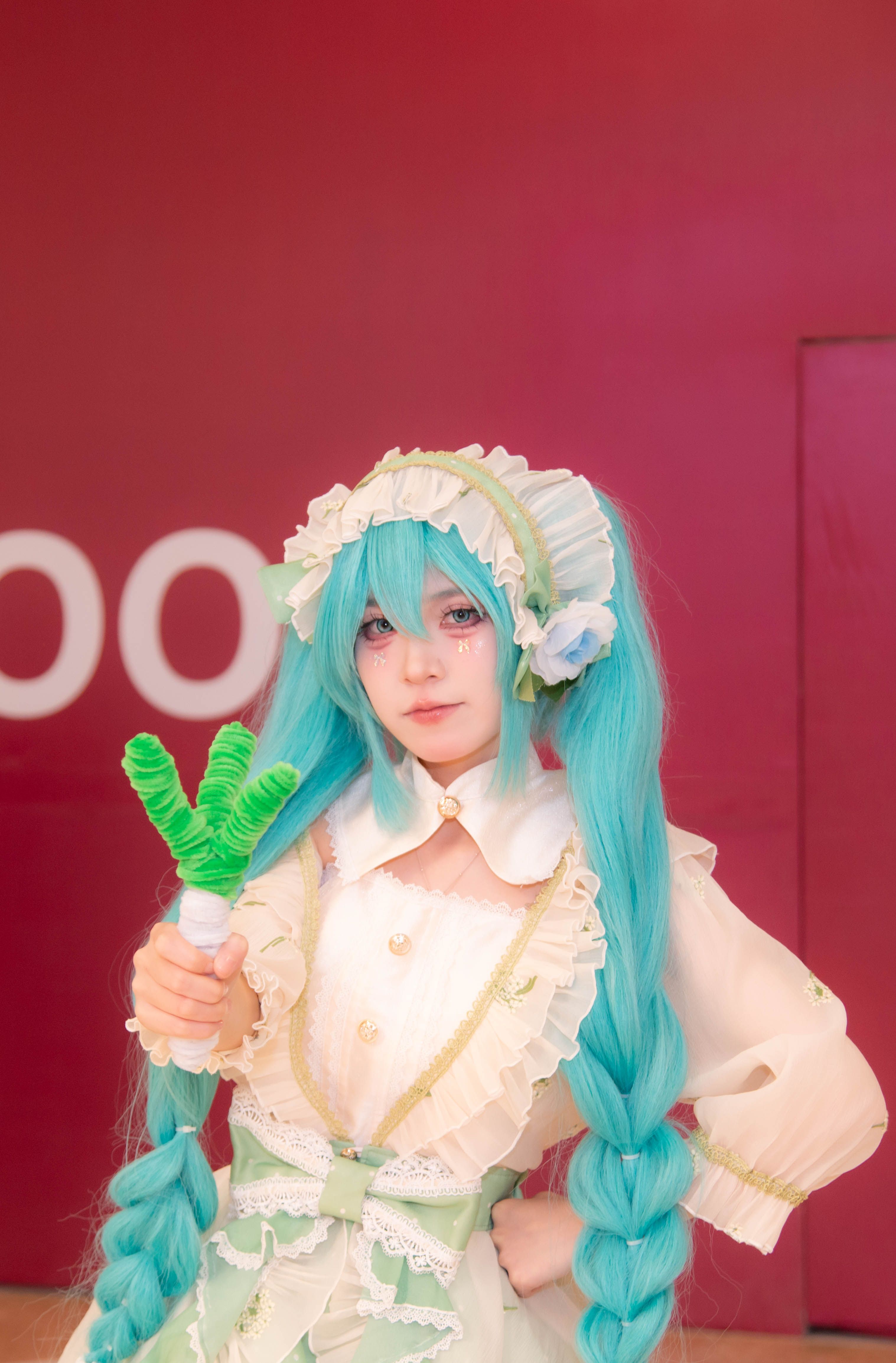 Vibrant cosplay of a popular anime character with long turquoise hair and detailed costume.