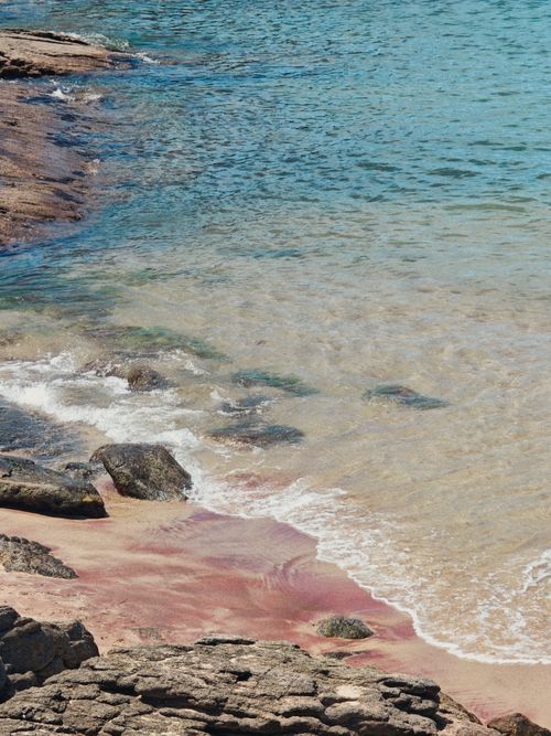 Free Peaceful view of a rocky shoreline with unique pink sand in Guarapari, Brazil. Stock Photo