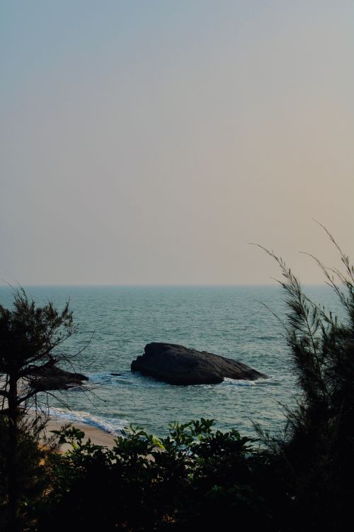 Free Serene coastal view featuring rocks and calm sea at sunset, perfect for travel and relaxation themes. Stock Photo