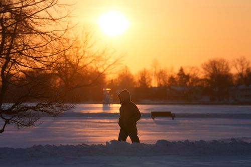 Free Silhouetted figure walking through snow at sunset, capturing a serene winter moment. Stock Photo