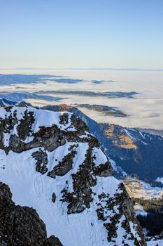 Breathtaking view of snow-covered Mount Pilatus with a blanket of clouds and distant mountains.