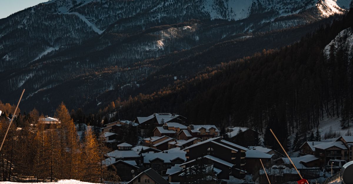 A picturesque snowy village nestled in the mountains during winter with clear skies.