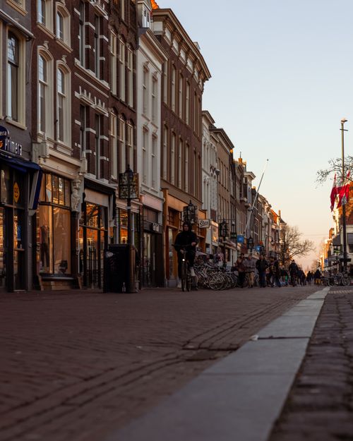 Free Historic Gouda street at twilight with cyclists, showcasing traditional Dutch architecture. Stock Photo