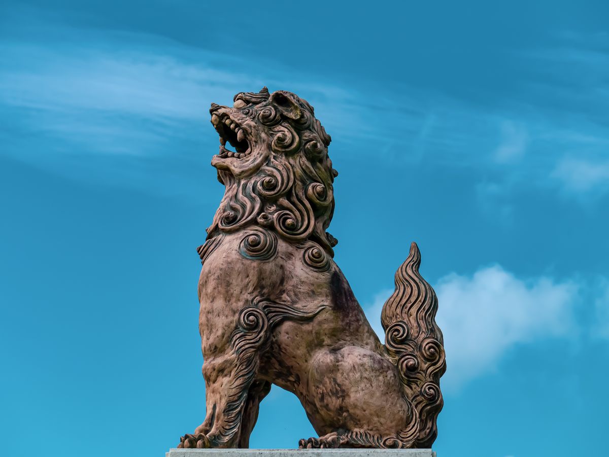 Majestic Shisa statue with intricate design set against a vibrant blue sky, symbolizing protection and cultural heritage.