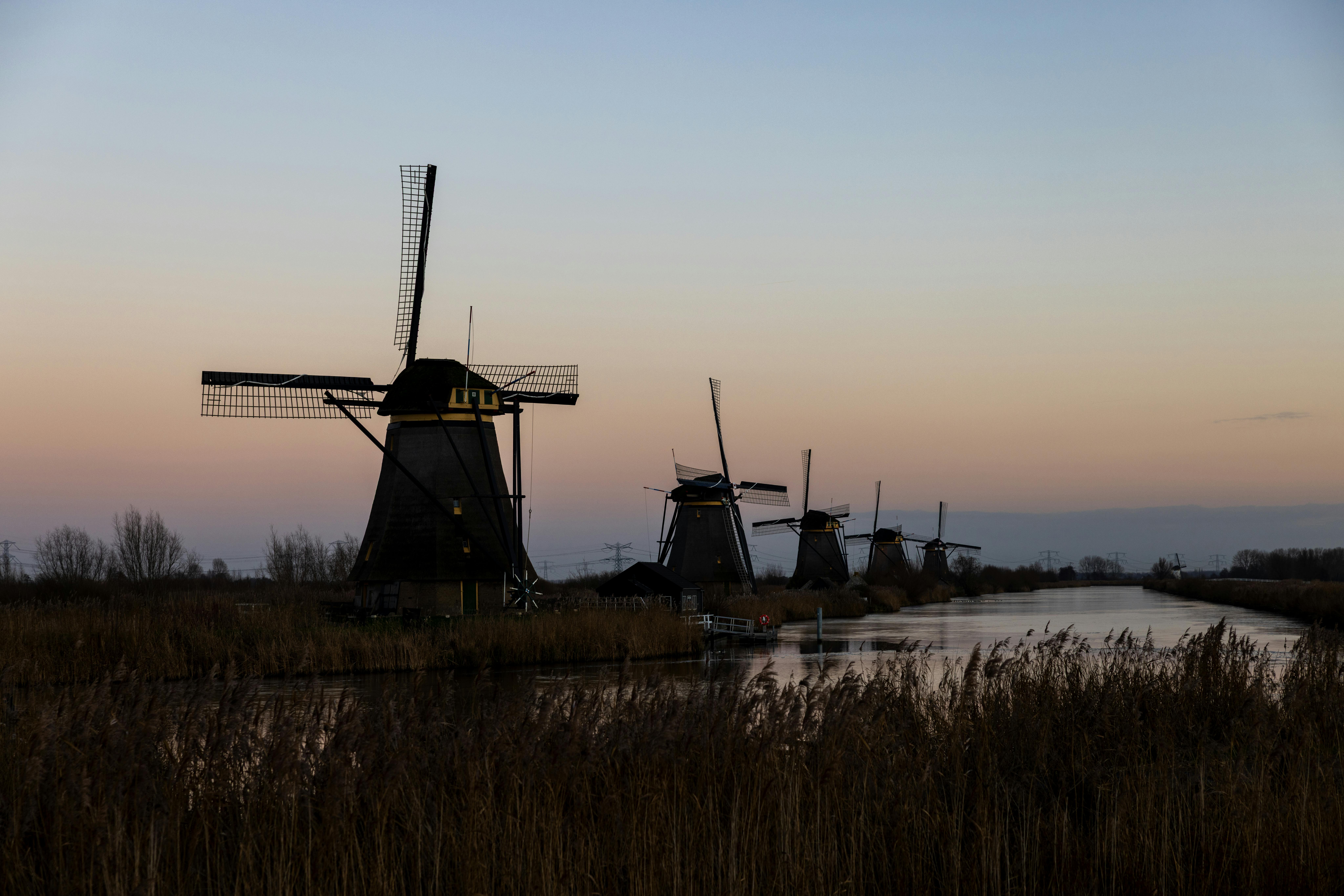 Captivating sunset view of iconic Kinderdijk windmills reflecting on the waterway.
