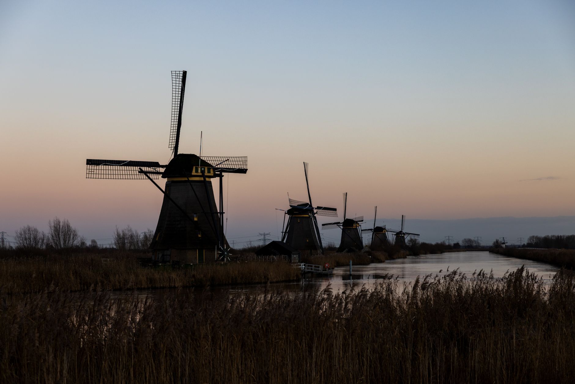 Captivating sunset view of iconic Kinderdijk windmills reflecting on the waterway.