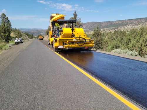 Free Road construction with paving machine in rural Oregon, highlighting infrastructure development. Stock Photo
