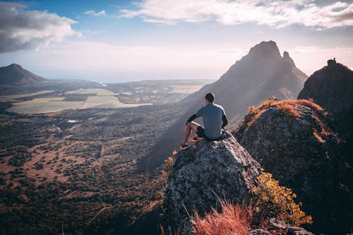 Homme En Chemise Grise Assis Sur Rock Mountain