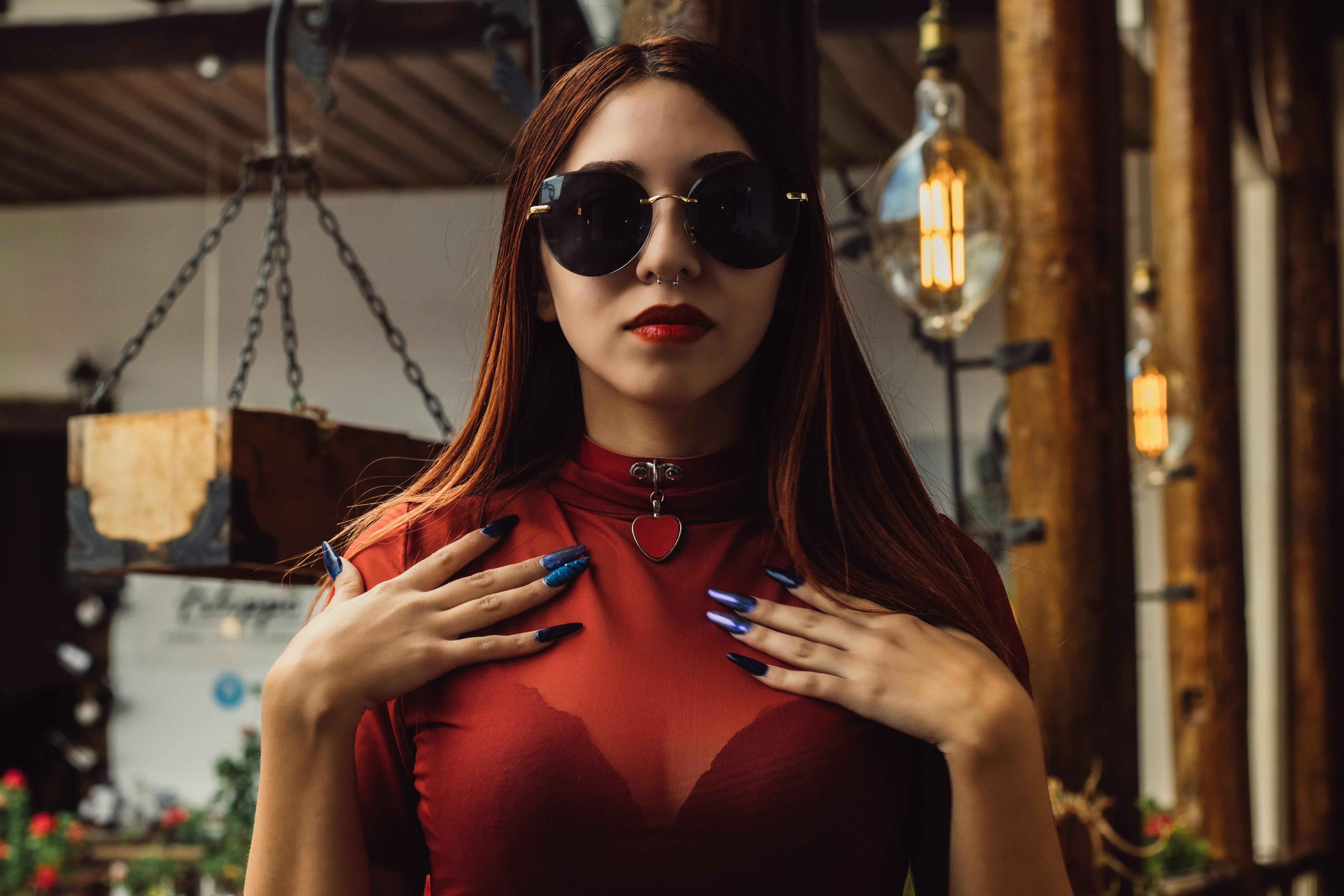 Gratuit Femeie la modă, cu ochelari de soare și ținută roșie, pozând în interior, cu un fundal elegant. Fotografie de stoc