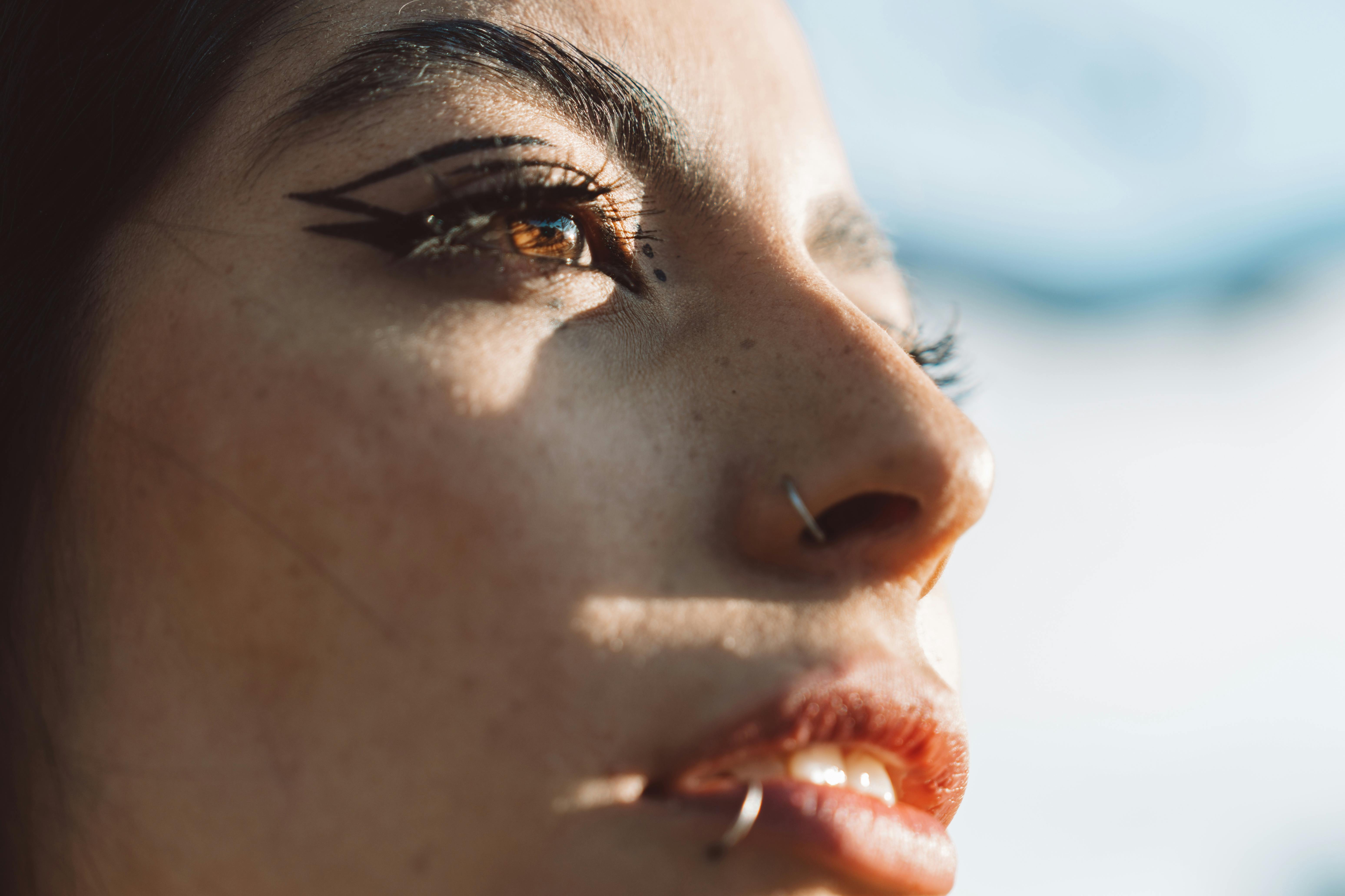 無料 自然光の中で、大胆なアイライナーを引いた女性の顔を親密にクローズアップした写真です。 写真素材