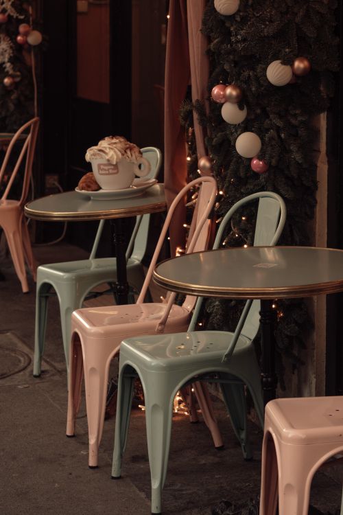 Free Charming Paris café decorated for winter, featuring pastel chairs, hot chocolate, and croissants. Stock Photo