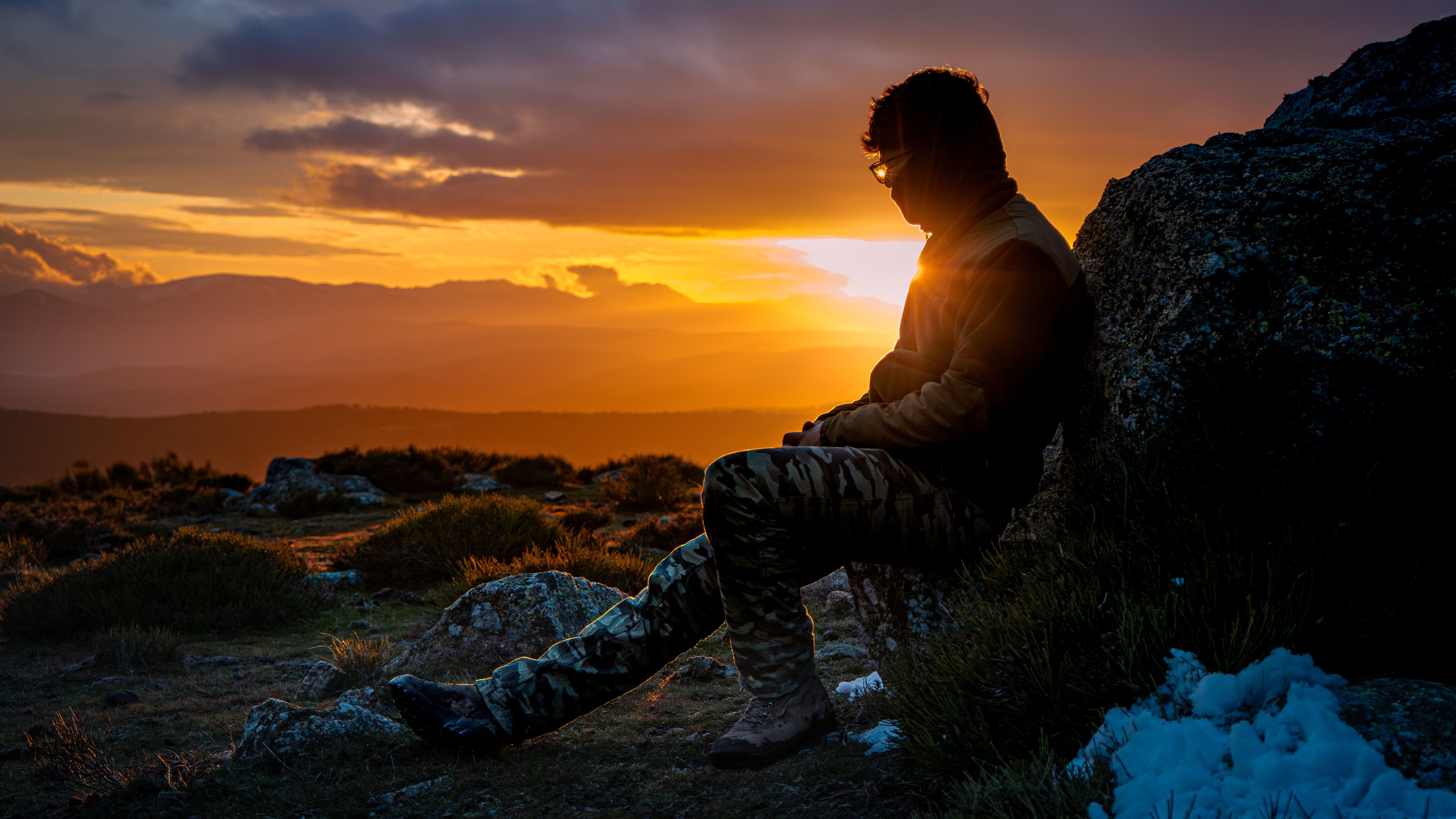 Silhouette of a person standing contemplatively at sunset, representing reflection and resilience