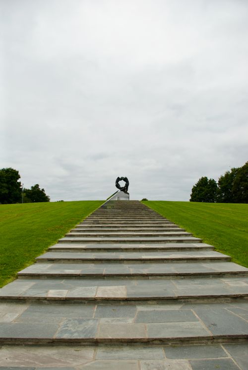 Free Wide stone steps ascend to a unique sculpture on a grassy hill in a park in Oslo. Stock Photo