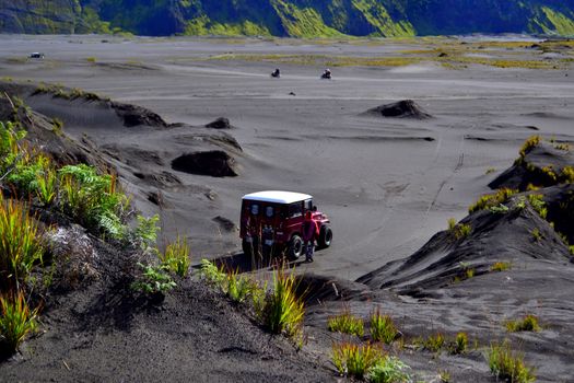A jeep navigates the rugged volcanic landscape in East Java, Indonesia, offering a thrilling adventure.