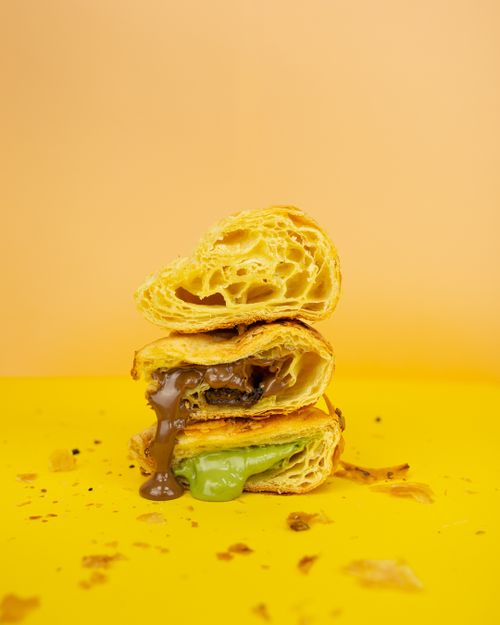 Free Stacked pastries with oozing chocolate and green fillings on a vibrant yellow backdrop. Stock Photo