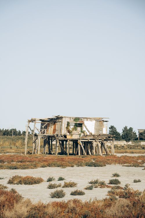 Free A weathered wooden shack stands isolated in an arid field with wild vegetation in Baku, Azerbaijan. Stock Photo