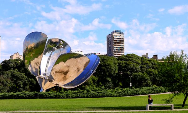 Floralis Generica sculpture in a Buenos Aires park with buildings in the background.