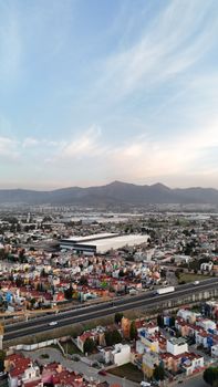 Aerial view of colorful urban cityscape with mountains in the background at dusk.