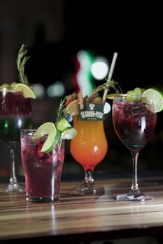 Colorful cocktails with fresh garnishes on a wooden surface, perfect for social gatherings.