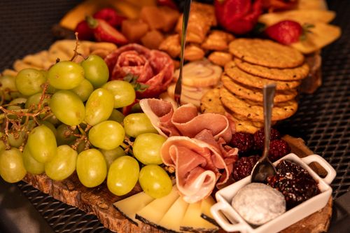 Free Elegant charcuterie board featuring grapes, cheese, prosciutto, and crackers. Stock Photo
