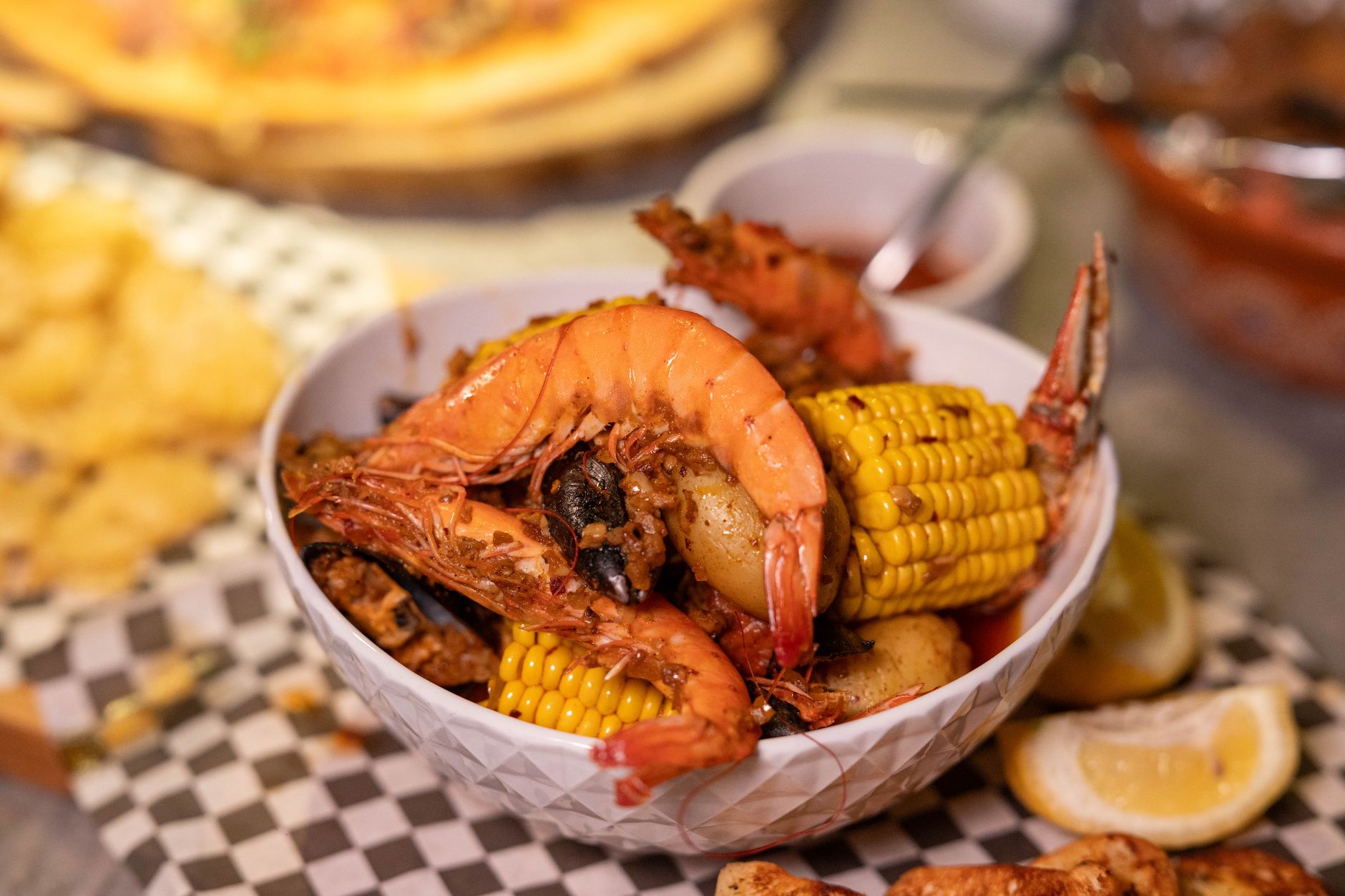 A vibrant crawfish boil spread with bright red seasoning coating crawfish, corn, potatoes, and sausage