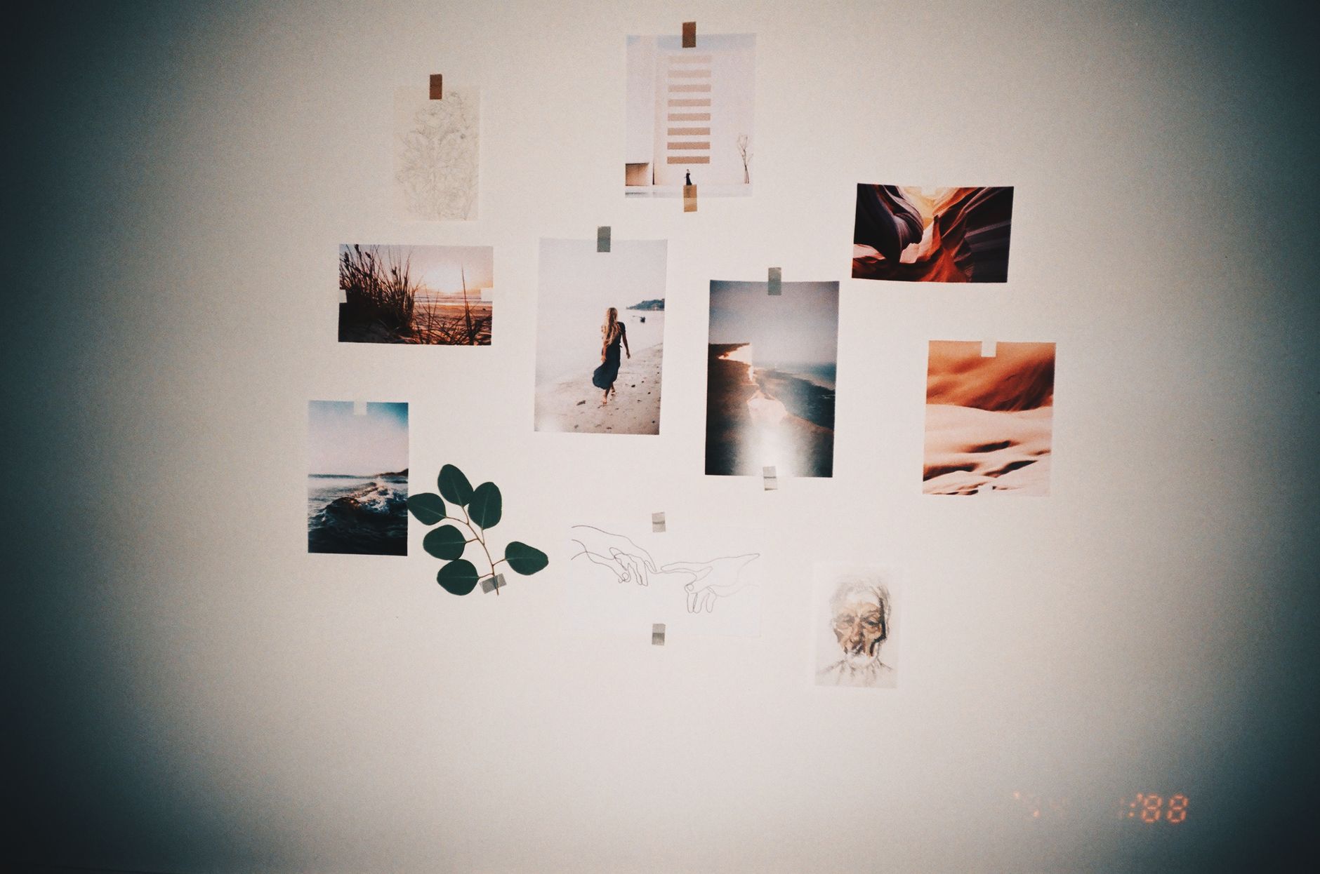 boho living room transformation with DIY hacks A stylish wall collage featuring photos and art prints taped on a light-colored wall, perfect for modern home decor.