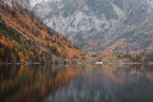 Stunning autumn landscape featuring a tranquil alpine lake with colorful foliage reflections.