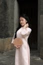 Young Woman in Ao Dai Holding a Fan Outdoors