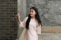 Woman in Traditional Outfit Against Brick Wall