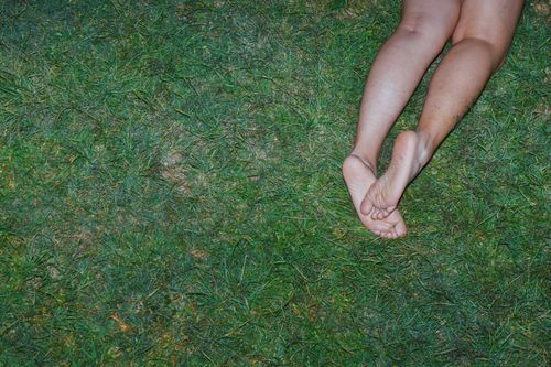 Free A person lying on lush grass, showing bare legs and feet, conveying relaxation. Stock Photo