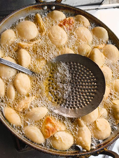 Free Top view of dumplings frying in oil with perforated ladle. Perfect for culinary themes. Stock Photo