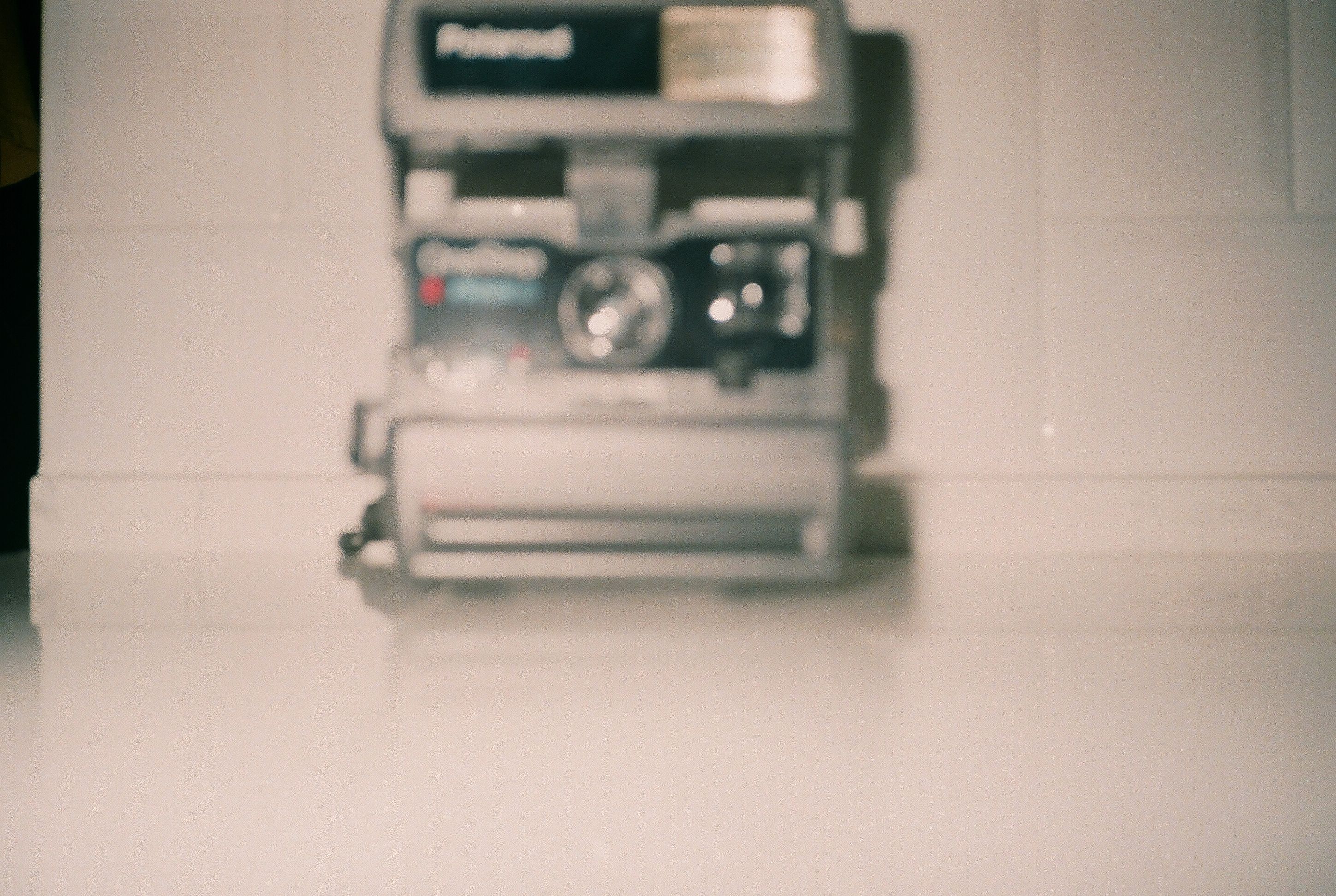 Blurred vintage Polaroid camera on a white surface creating a nostalgic feel.