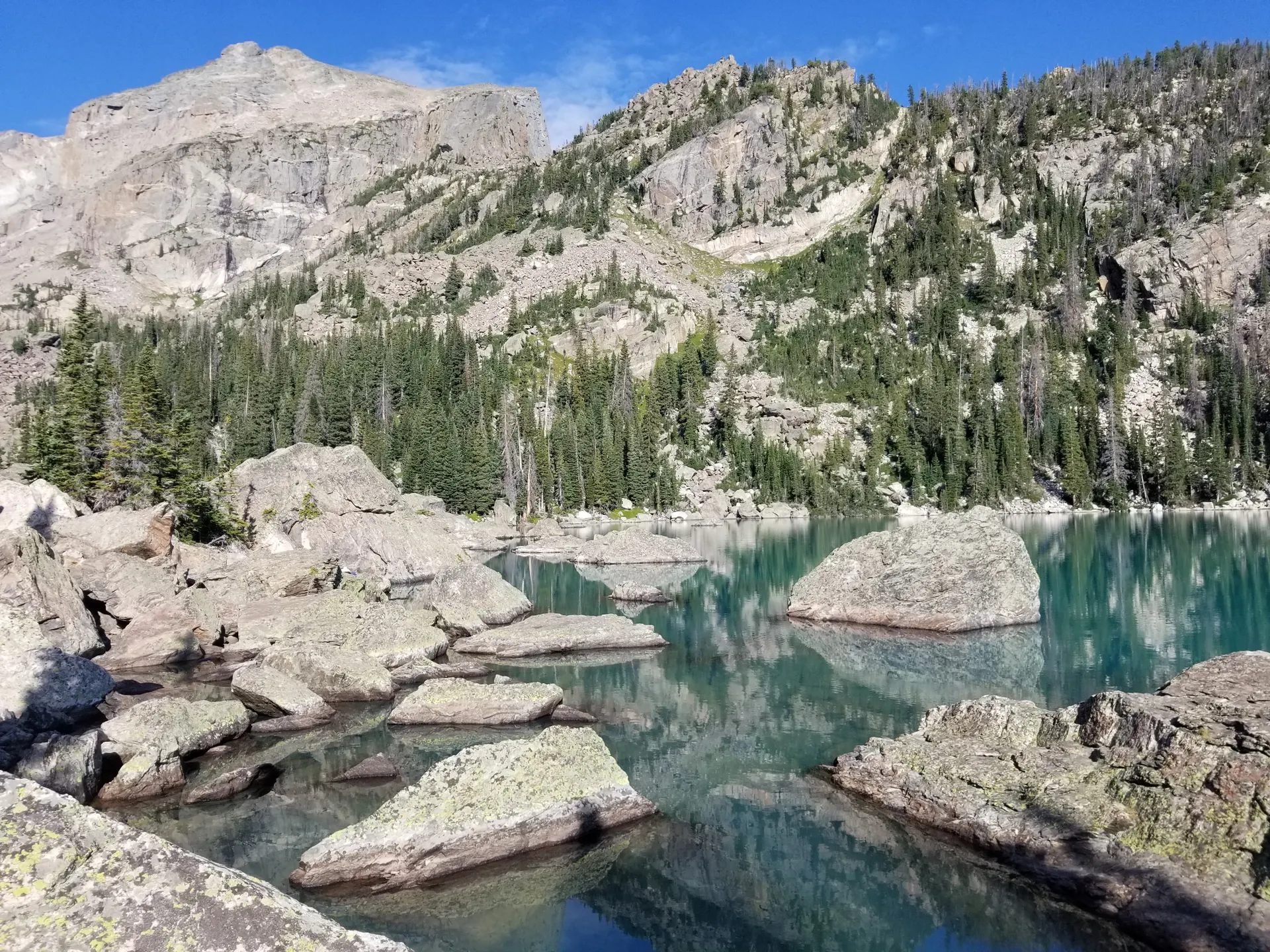 A tranquil alpine lake ringed by rocky peaks and evergreens in the Colorado Rockies A tranquil alpine lake ringed by rocky peaks and evergreens in the Colorado Rockies