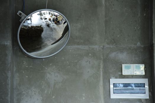 Circular mirror reflecting modern indoor space on textured concrete wall.
