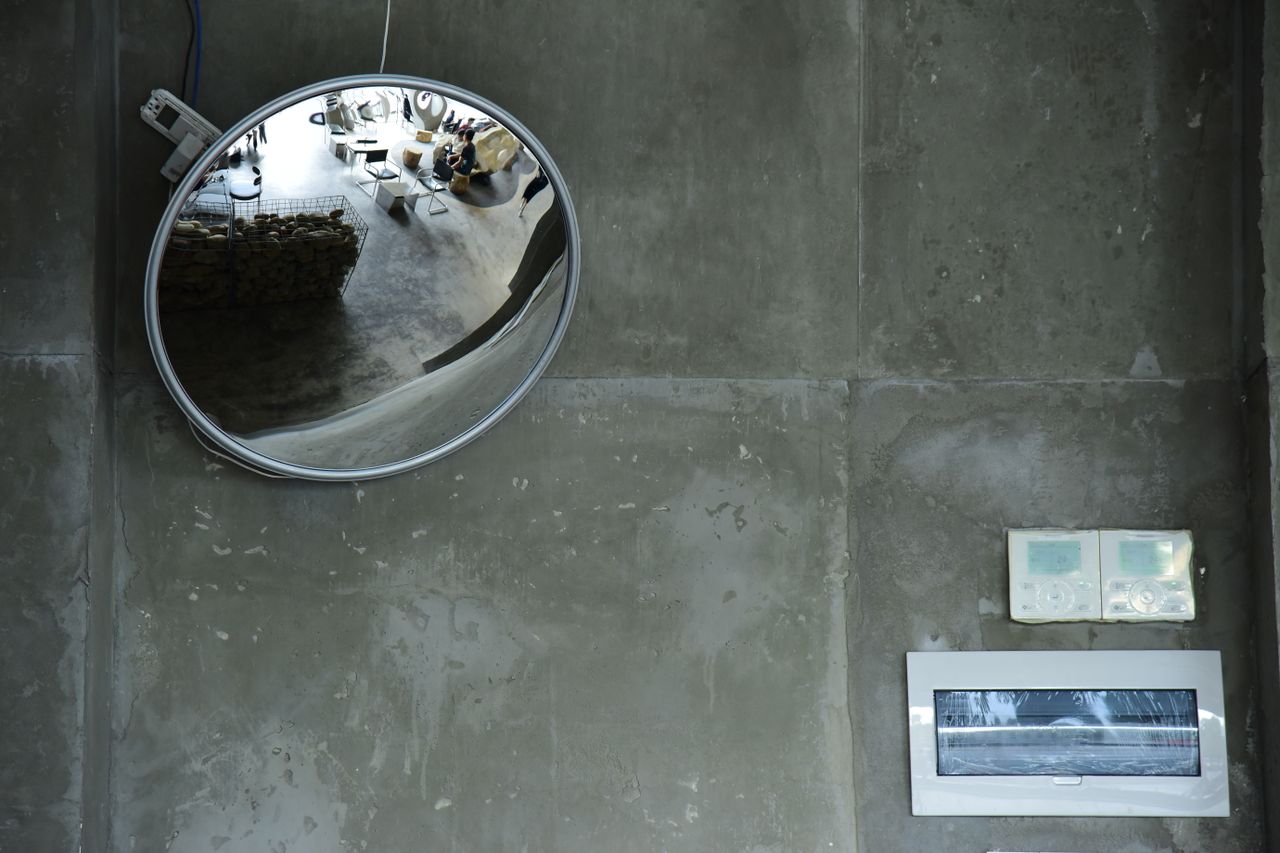 circular mirror reflecting modern indoor space on textured concrete wa