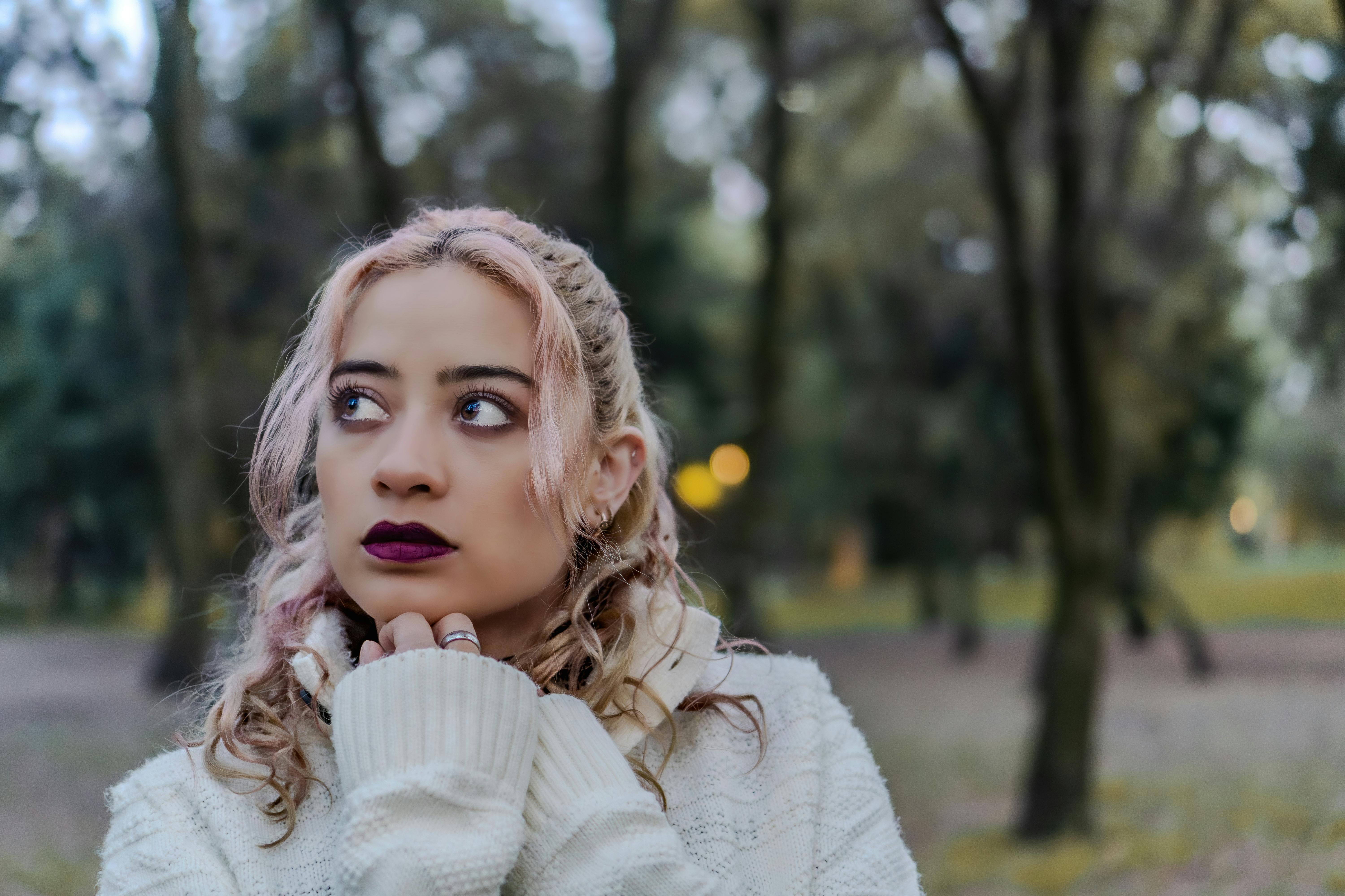 免費 一位身穿舒適毛衣的沉思女子站在秋日的森林中。 圖庫相片