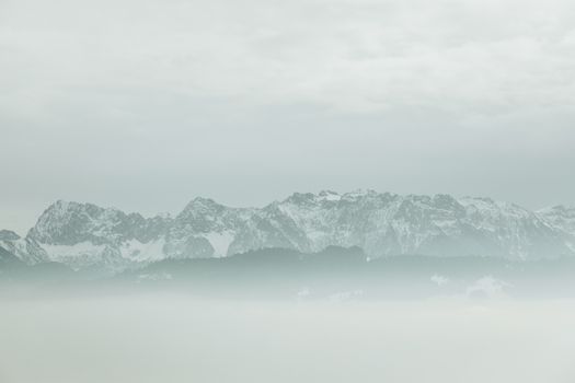 Captivating snowy mountain range shrouded in mist, evoking winter's serene beauty.
